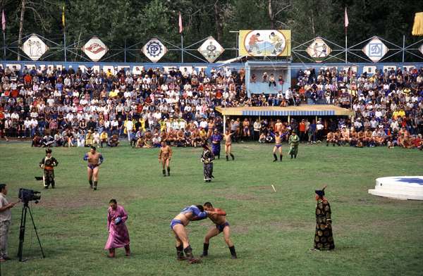 photo of Tuva, Kyzyl, wrestling match, the men perform the dance of the eagle, clad in hand-embroidered garb, and parade in front of spectators. They slap the front and back of their thighs and then spar with a partner trying not to touch the ground except with the palms of their hands or their feet
